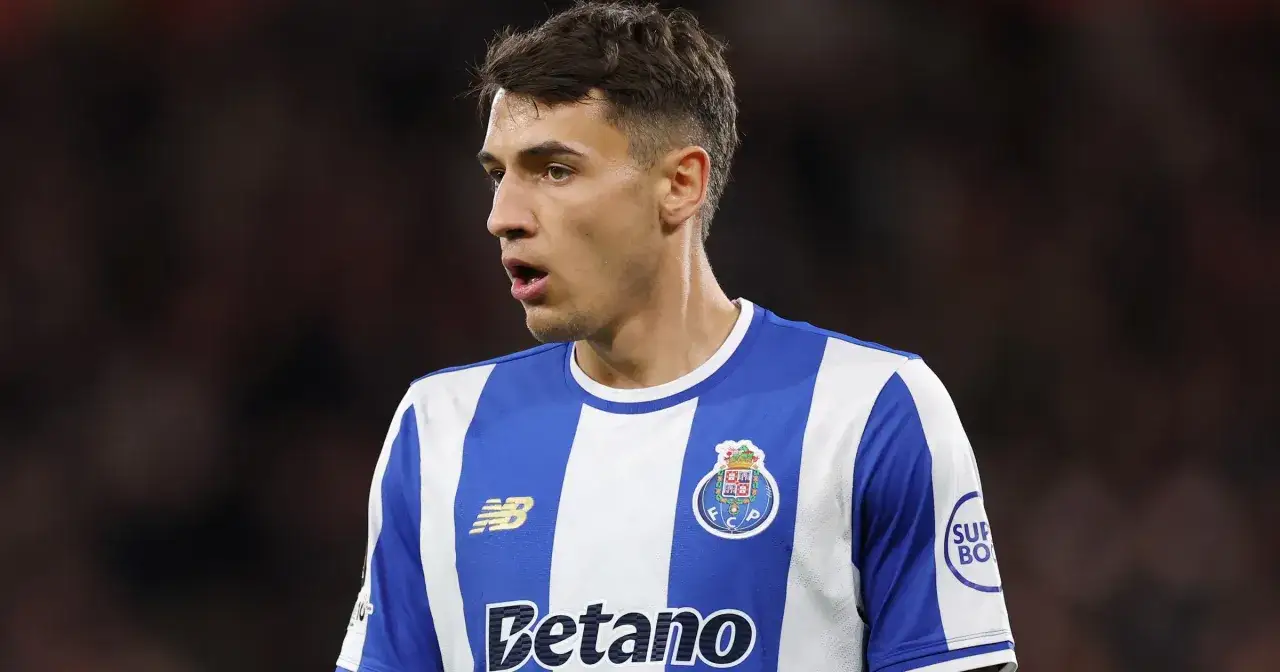 Piłkarz w niebiesko-białej koszulce FC Porto, gdzie gra Kiwior, z uwagą śledzi akcję na boisku.