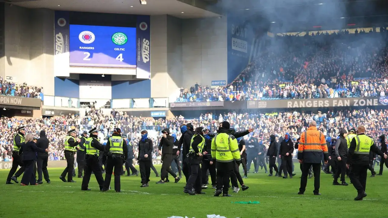 Na boisku stadionu, gdzie lokalny rywal piłkarzy Glasgow Rangers, Celtic, wygrywa 4:2, interweniuje policja i ochrona wśród dymu i kibiców.