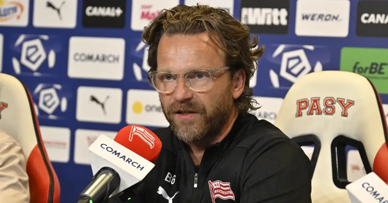 Trener Cracovii w okularach przed mikrofonem Comarch.