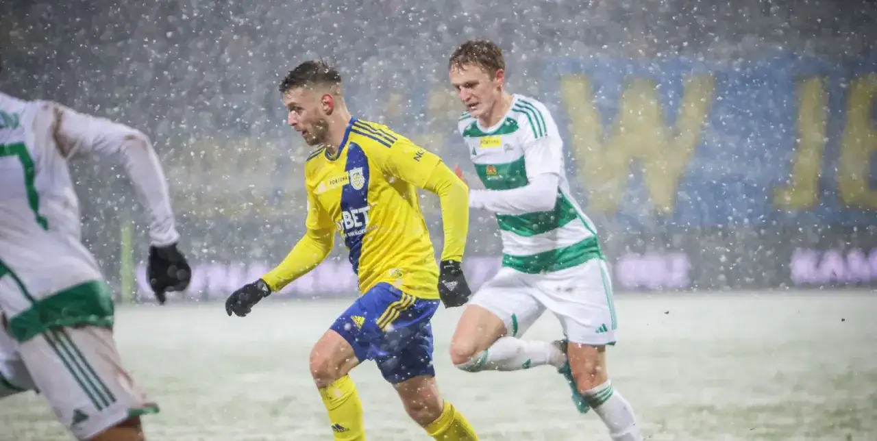 Piłkarze Arki Gdynia i Lechii Gdańsk walczą o piłkę w śnieżycy.