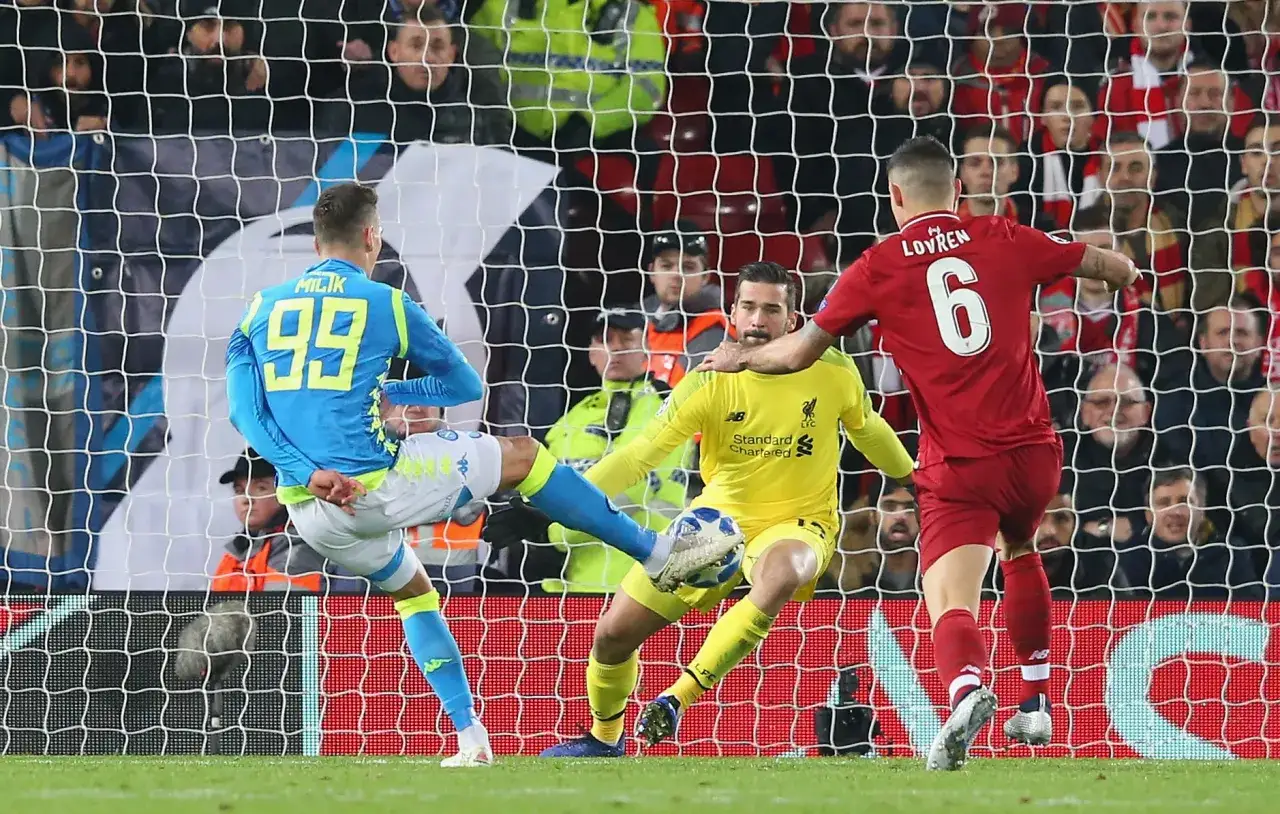 Piłkarz Napoli z numerem 99 próbuje strzelić gola, ale bramkarz Liverpoolu, Alisson, broni. To był ważny mecz dla Liverpoolu, który wielokrotnie wygrał Ligę Mistrzów.