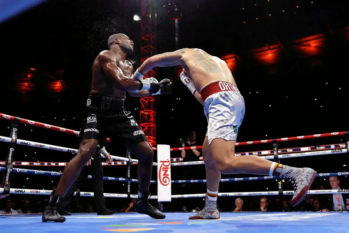 Usyk w akcji, buduje swój imponujący rekord. Dwóch bokserów w ringu, jeden wyprowadza cios.