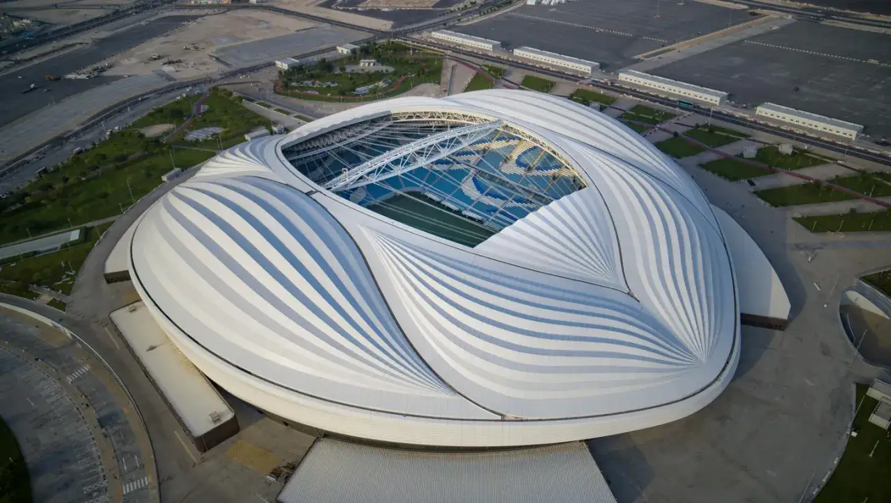 Futurystyczny stadion z białym, falującym dachem, który wielu uważa za najładniejszy stadion na świecie. Widać zieloną murawę i niebieskie trybuny.