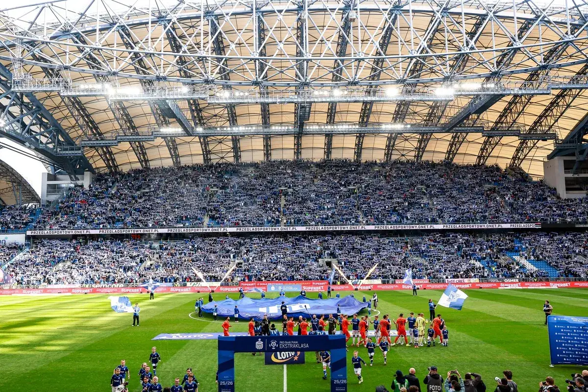 Piłkarze wychodzą na murawę stadionu, a trybuny wypełnione kibicami. Zastanawiasz się, ile meczy zostalo w ekstraklasie?