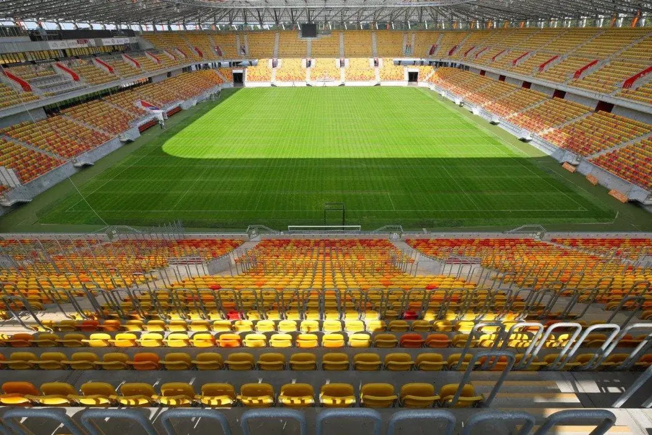 Pusta trybuna stadionu Jagiellonii, żółte i czerwone krzesełka czekają na kibiców. Stadion jagiellonii pojemność robi wrażenie.