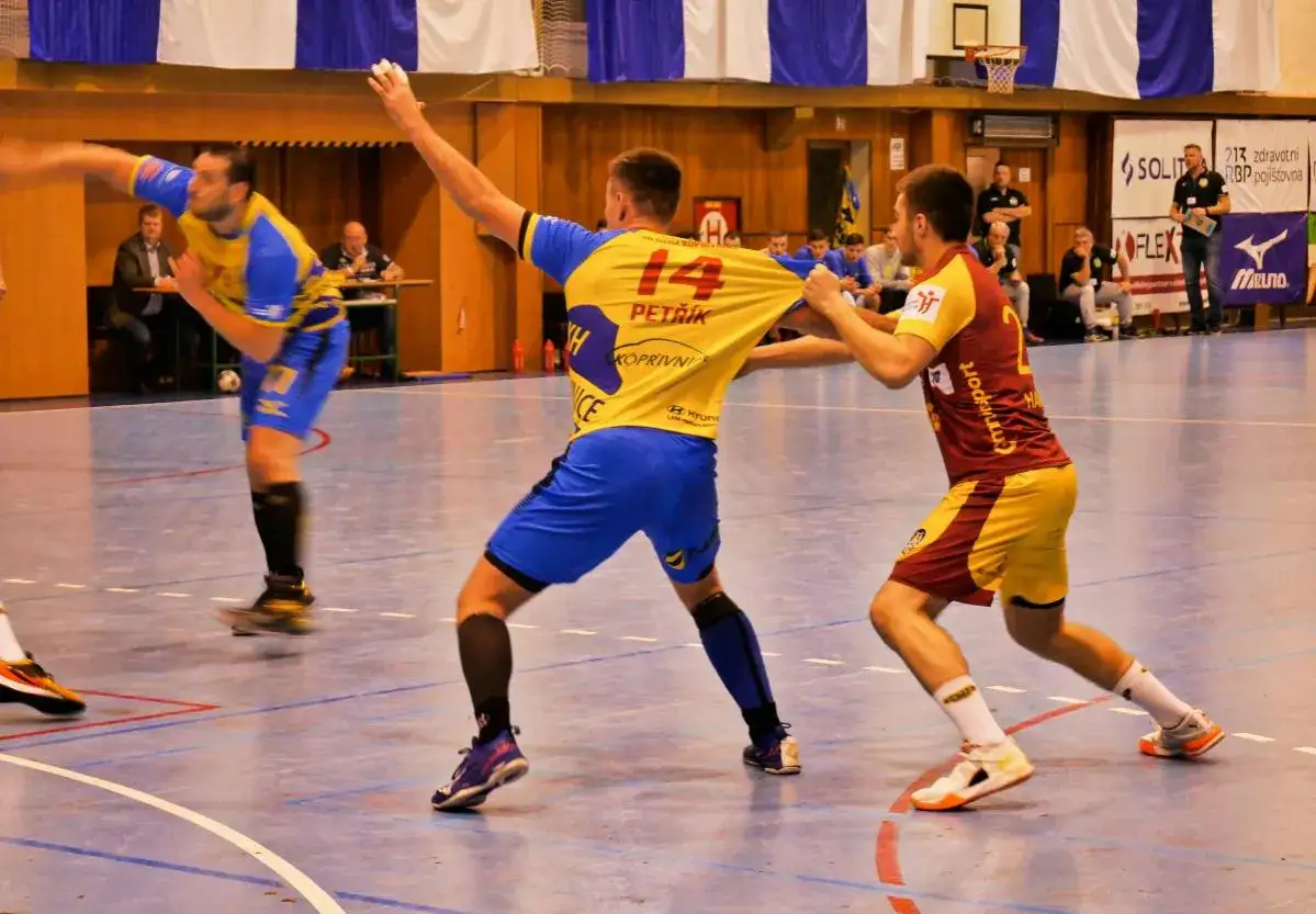 Piłkarz ręczny w żółtej koszulce z numerem 14 szarpany przez przeciwnika. To może być sytuacja, która oznacza czerwoną kartkę w piłce ręcznej.