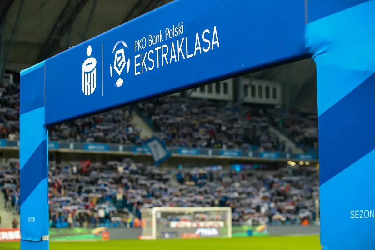 Brama z logo PKO Bank Polski Ekstraklasa na tle trybun pełnych kibiców. Czas na emocje, kiedy terminarz ekstraklasy wzywa!