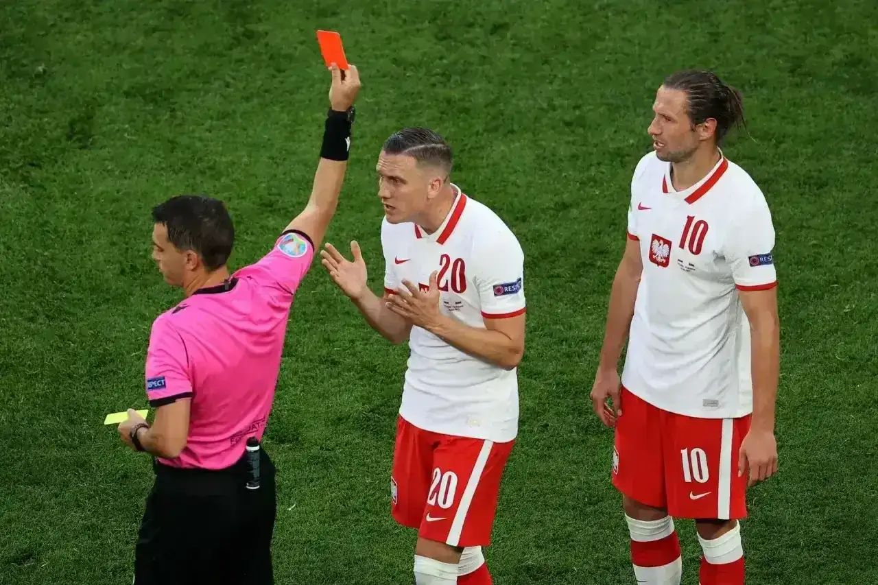 Sędzia pokazuje czerwoną kartkę w piłce nożnej zawodnikowi reprezentacji Polski.