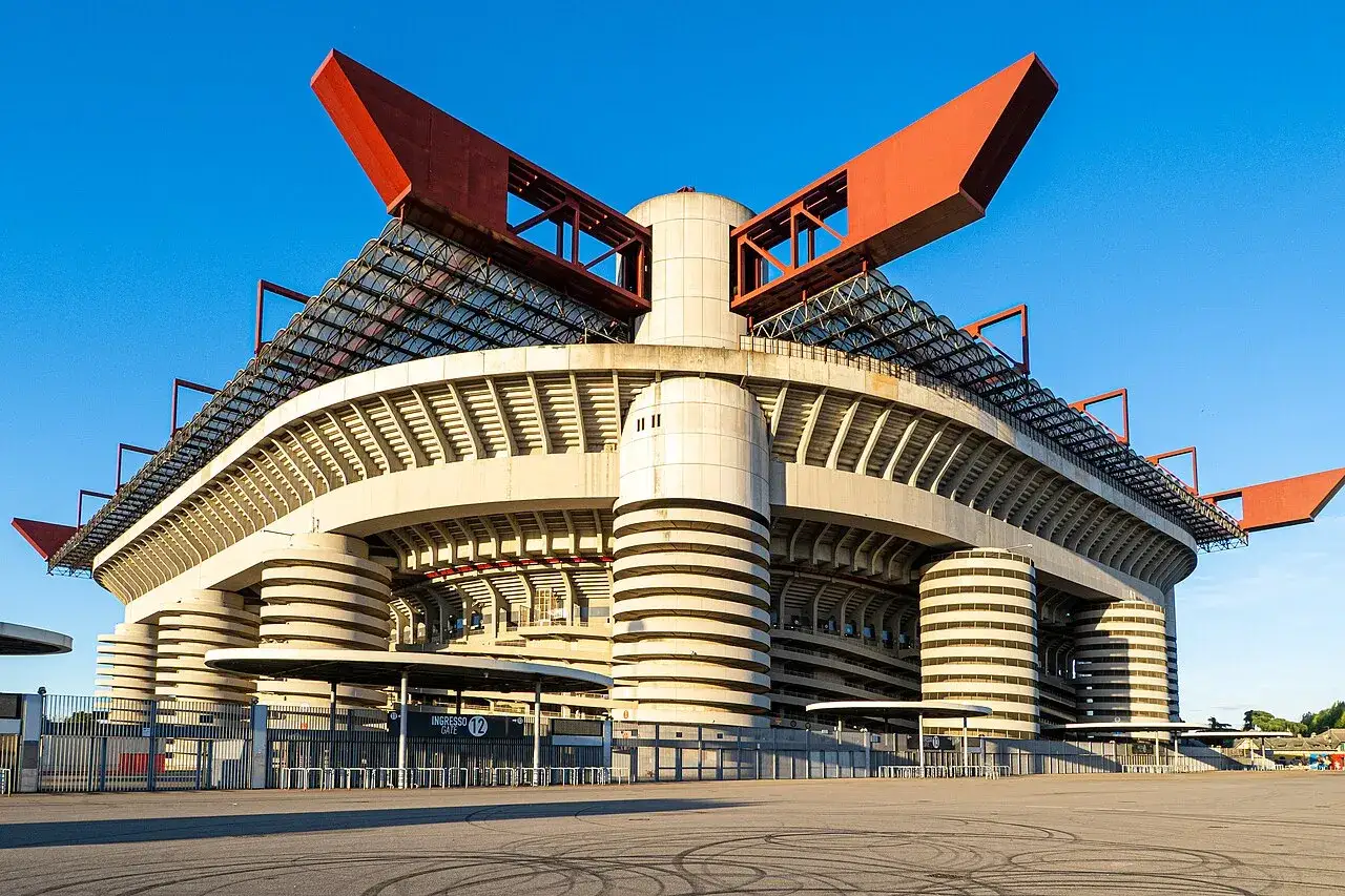Imponujący mediolan stadion z charakterystycznymi czerwonymi elementami dachu i betonowymi kolumnami, gotowy na przyjęcie kibiców.
