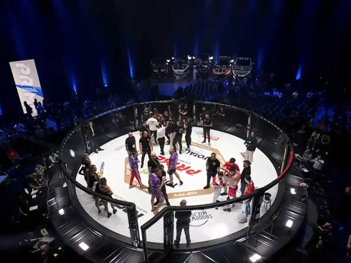 Widok z góry na ring MMA podczas gali Prime. Zawodnicy w narożnikach, tłum kibiców i światła sceniczne tworzą atmosferę wielkiego wydarzenia.
