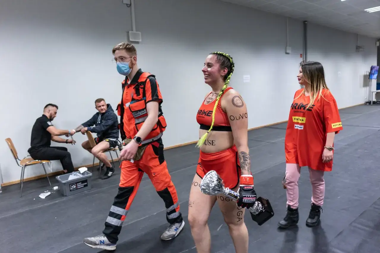 Zawodniczka po freak fight z pucharem, obok ratownik medyczny i osoba w koszulce PRIME.