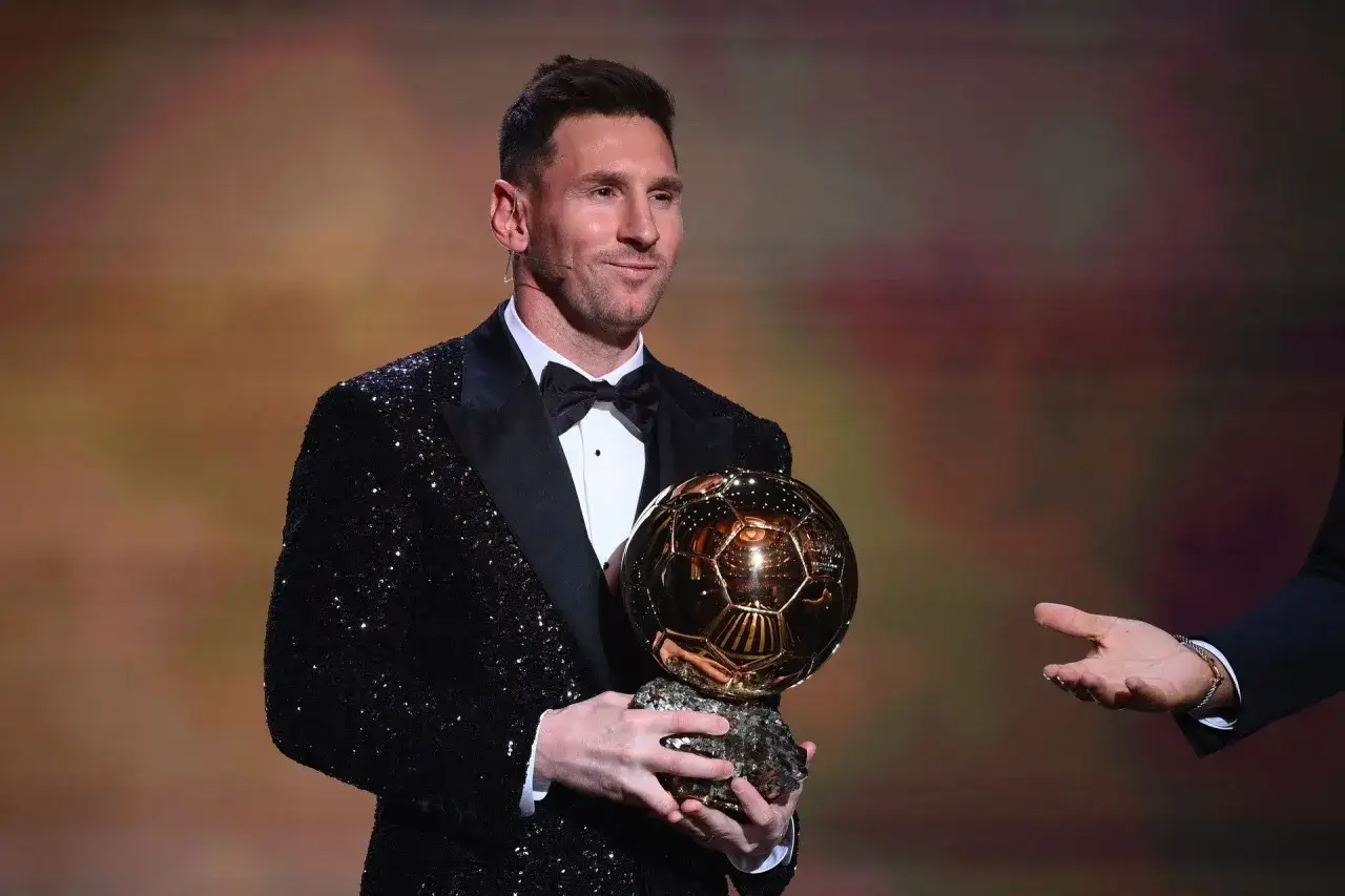 Lionel Messi w błyszczącym garniturze trzyma Złotą Piłkę.