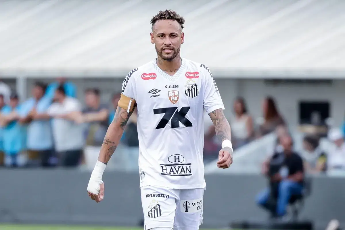 Neymar w białej koszulce Santos, gotowy do gry. Widać jego charakterystyczną fryzurę i tatuaże.