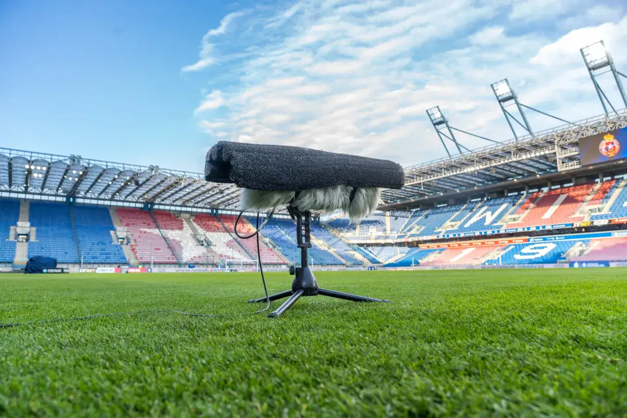 Mikrofon na statywie na pustym stadionie, gotowy do nagrania dźwięków, kto dziś gra w piłkę nożną.