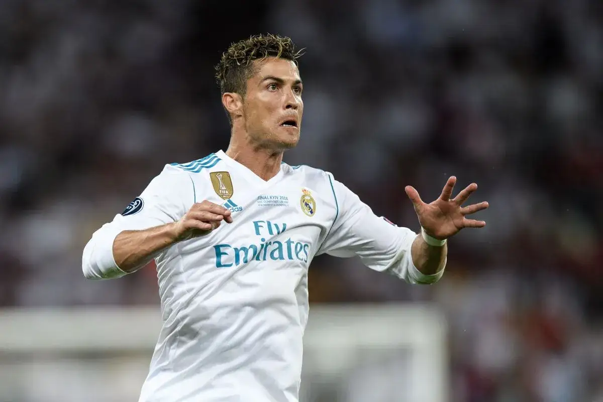 Cristiano Ronaldo w białej koszulce Realu Madryt, świętujący kolejne zwycięstwo. Ile Real Madryt ma pucharów Ligi Mistrzów? Tyle, ile on ma palców na tej dłoni, plus jeszcze kilka!