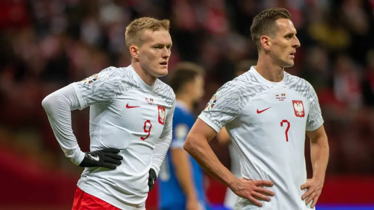 Dwóch piłkarzy reprezentacji Polski w białych strojach z orłem na piersi, z numerami 9 i 7.