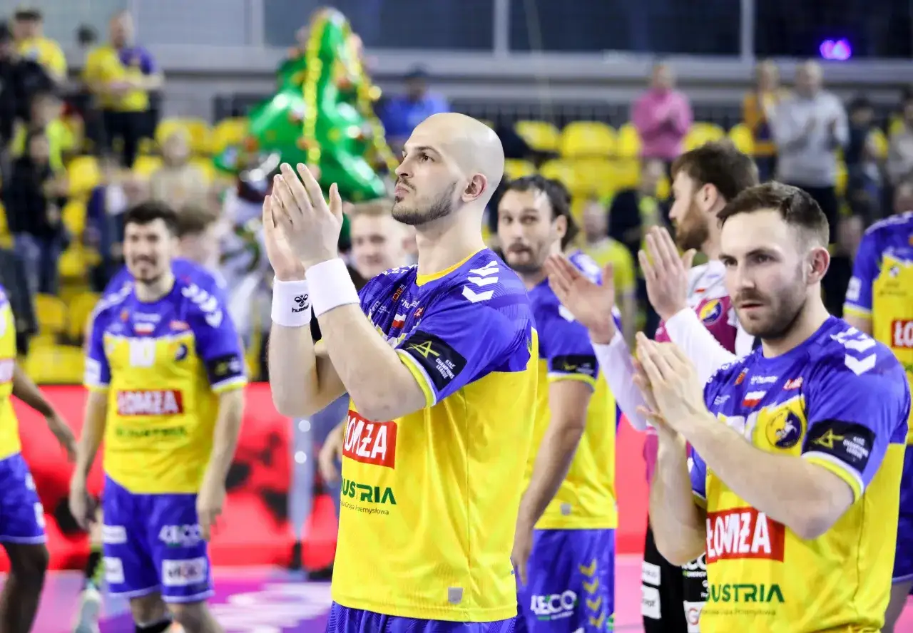 Piłkarze ręczni w żółto-niebieskich strojach klaszczą, świętując zwycięstwo w finale.
