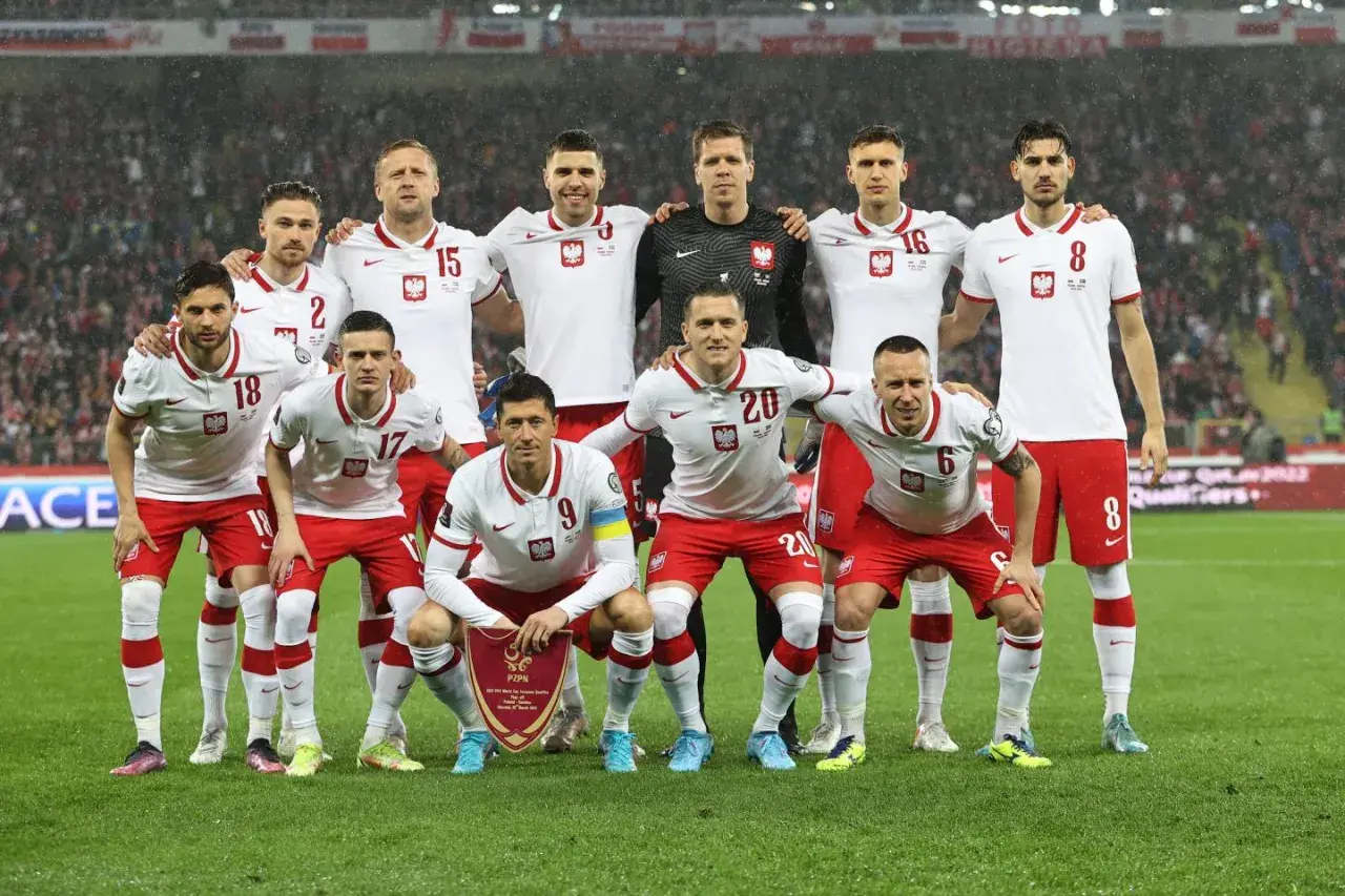 Piłkarze reprezentacji Polski w białych strojach, z orzełkiem na piersi, pozują do zdjęcia. Czy polska jedzie na mundial? Tak, ta drużyna walczy o awans!